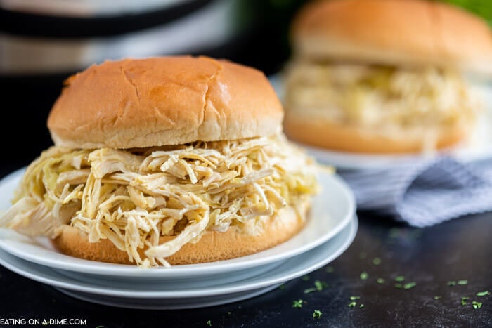 2 Mississippi Chicken Sandwiches on white plates in front of an Instant pot. 