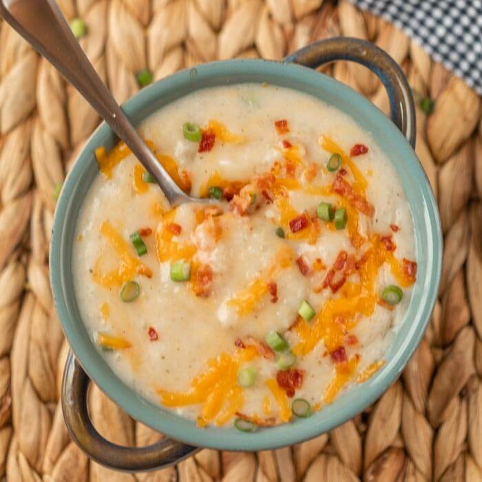 bowl of loaded potato soup with toppings and a spoon