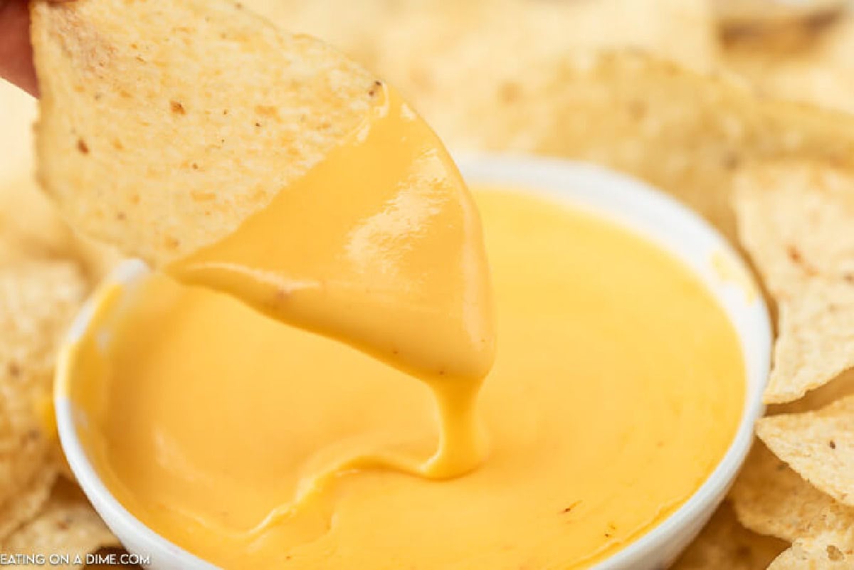 Tortilla chips dipping into the Homemade Nacho Cheese Sauce.