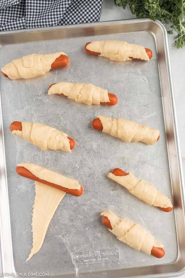 Uncooked pigs in a blanket on a baking sheet.