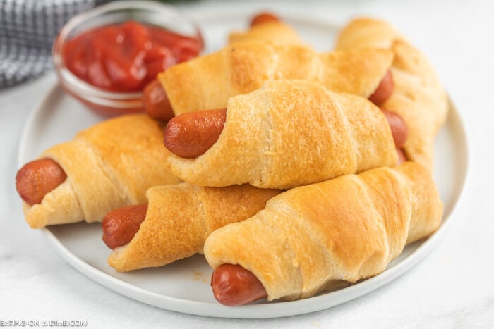 Plate of pigs in a blanket beside ketchup. 