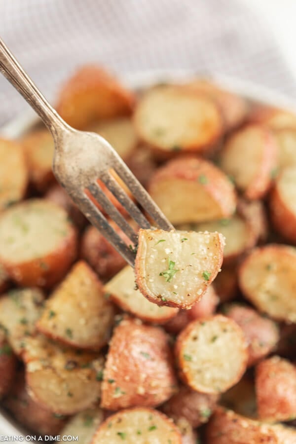 Serving dish of roasted red potatoes with a fork in the potatoes. 
