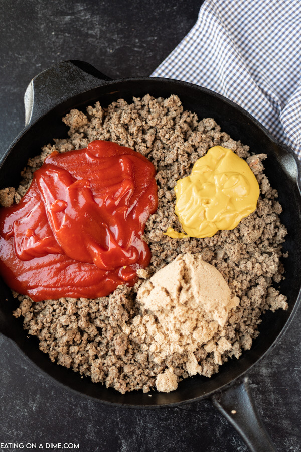 Close up image a cooked hamburger meat in a cast iron skillet ketchup, mustard and brown sugar. 