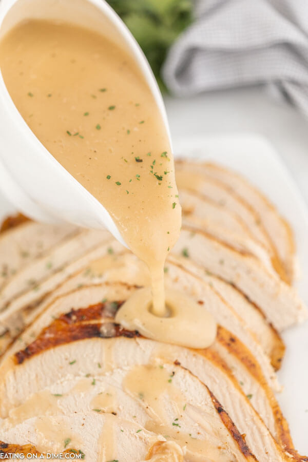This easy to make turkey gravy being pulled over sliced turkey breast 