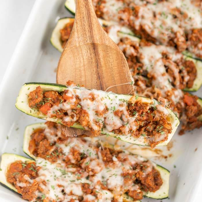 Baking pan of stuffed zucchini boats baked with cheese. 