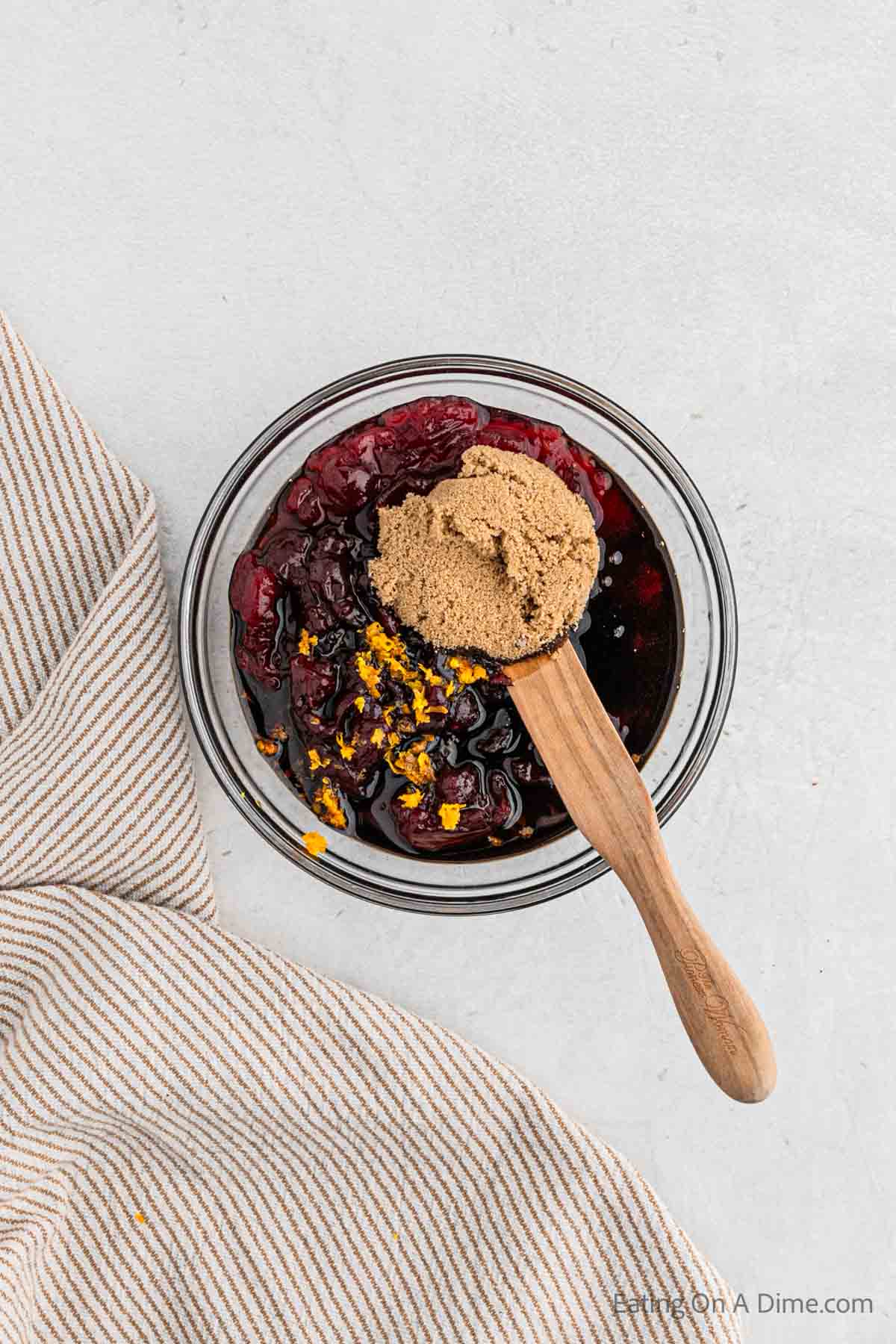 Combining the cranberry sauce ingredients in a bowl with a wooden spoon