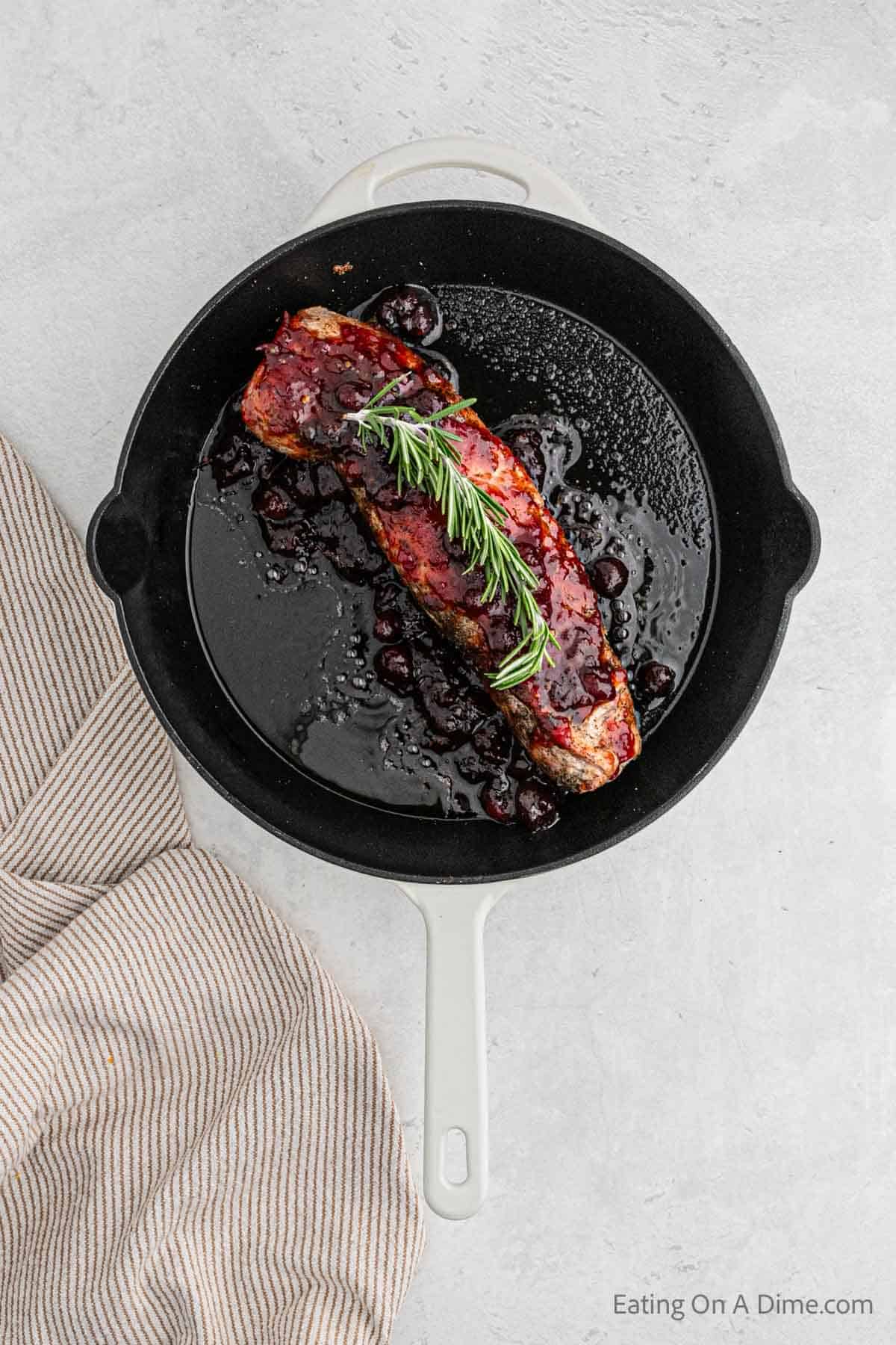 Topping the pork tenderloin with the cranberry sauce and rosemary sprig