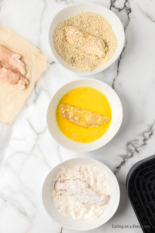 3 bowls with flour, eggs and bread crumbs for coating chicken tenders. 