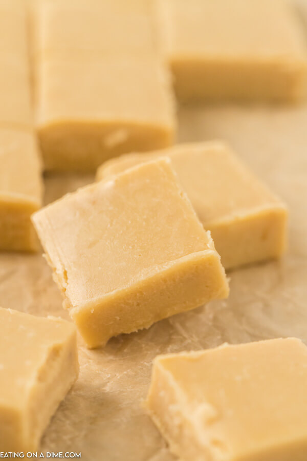Pieces of caramel fudge laying on each other on a piece of parchment paper.  