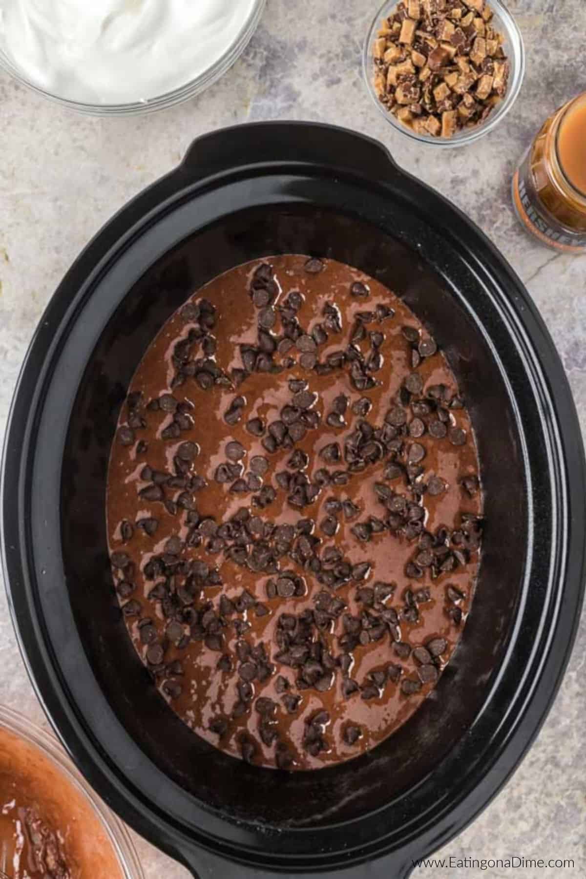Cake mix batter poured into the slow cooker and topped with chocolate chips.