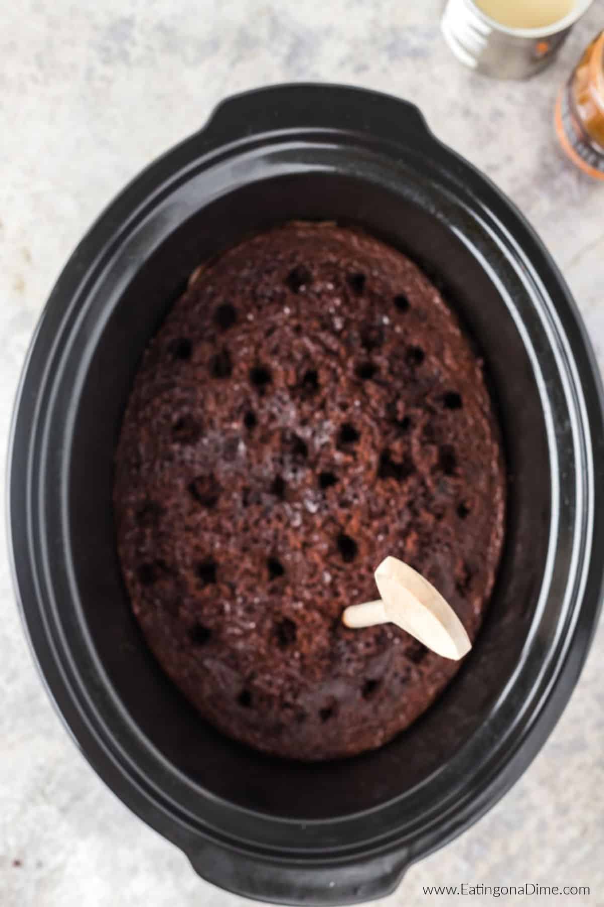 Poking holes in the cake in the crock pot.