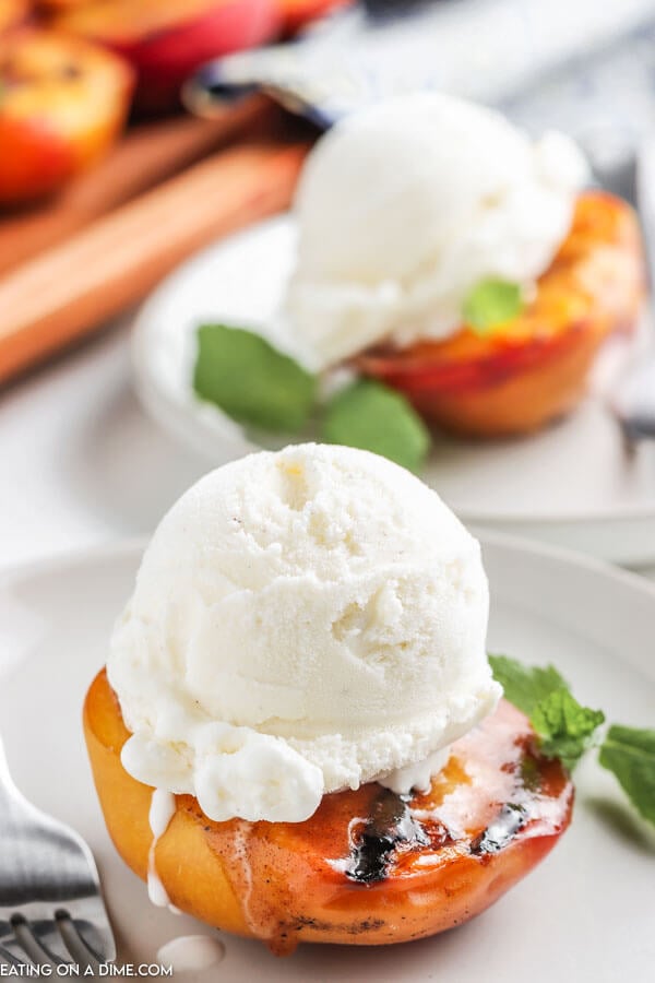 grilled peaches on a plate topped with a scoop of vanilla ice cream