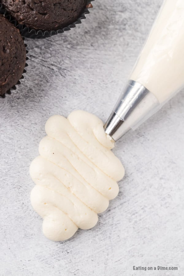 Close up image of frosting being piped from a bag. 