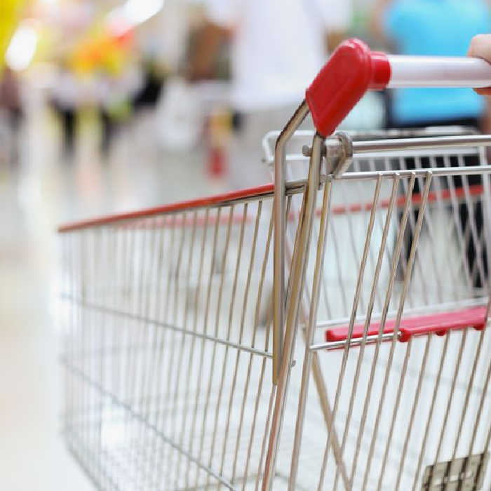 Close up photo of a shopping cart being pushed through the grocery store 