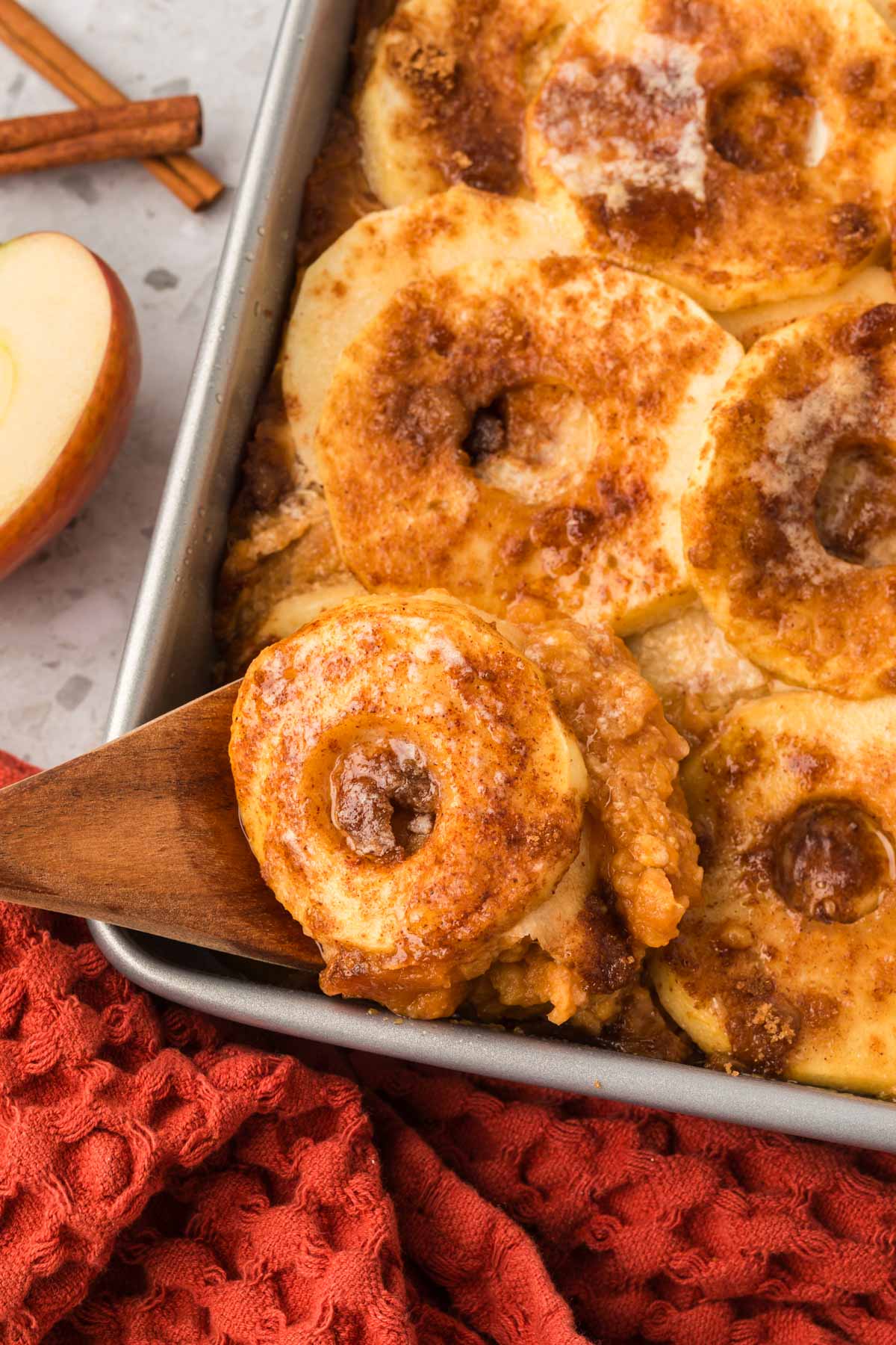 Sweet potato and apple casserole in a baking dish with a serving on a wooden spoon