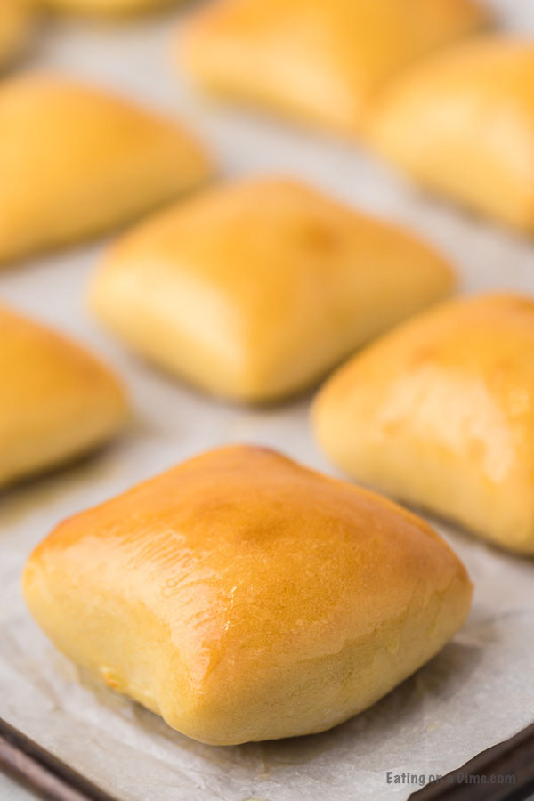 Baking sheet with fresh baked rolls lined with wax paper .