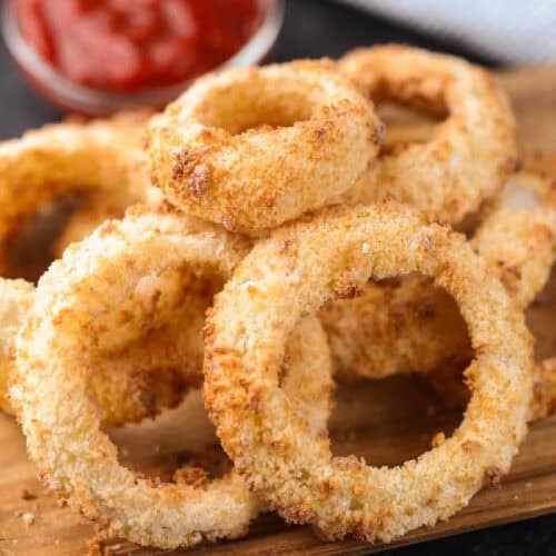Air Fryer Onion Rings on a wooden platter with a side of ketchup.