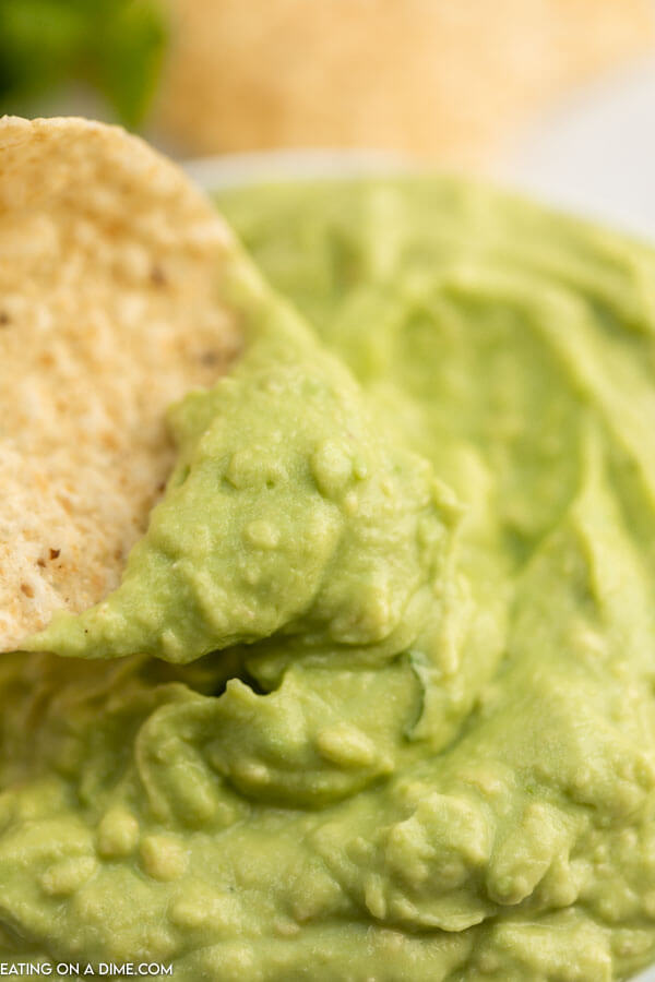 Up close picture of avocado dip and a tortilla chip. 