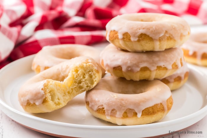 Close up image of glazed donuts stacked on a white plate. 