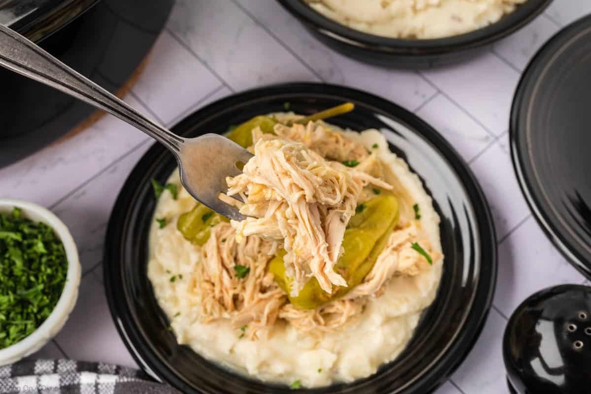 Shredded chicken with pepperoncinis served over mashed potatoes on a plate