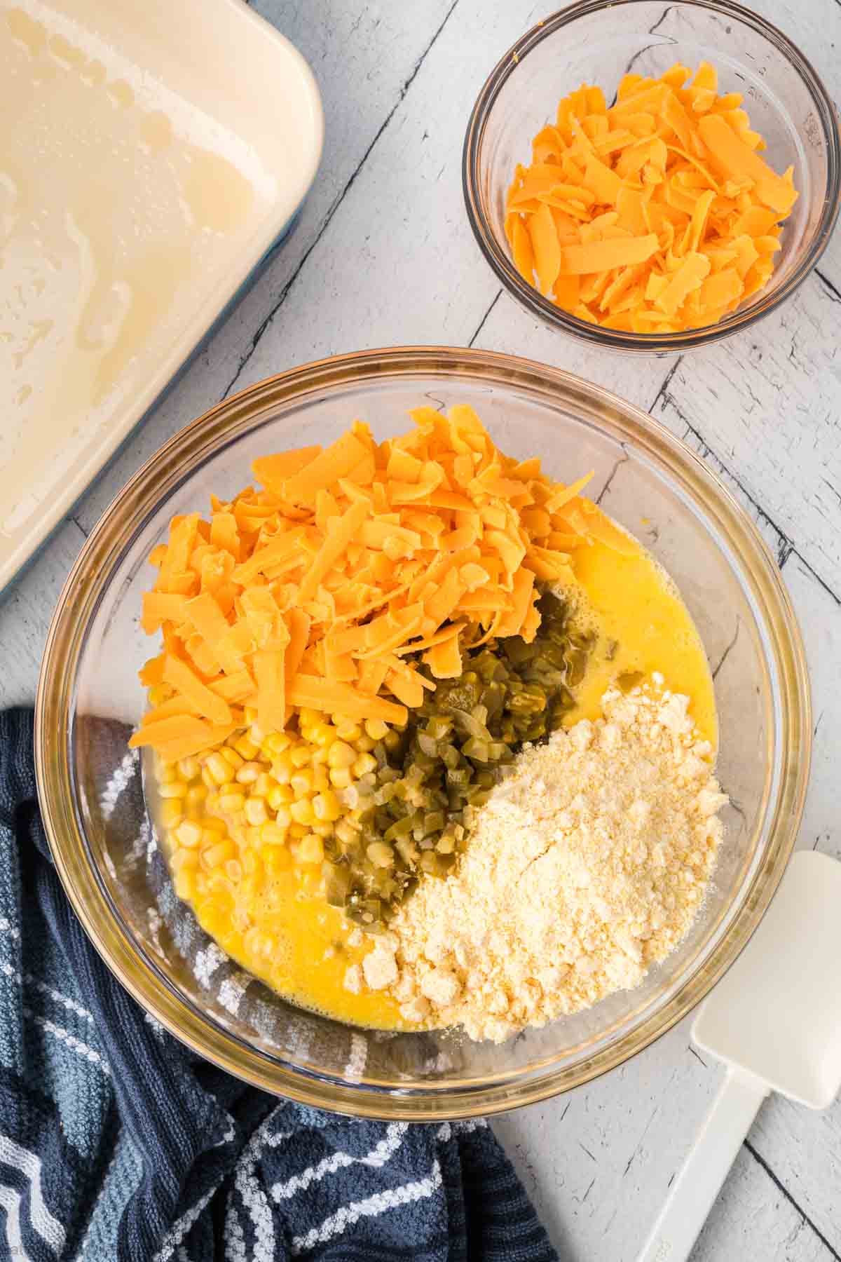 Adding in the remaining ingredients to the mixed eggs in a bowl