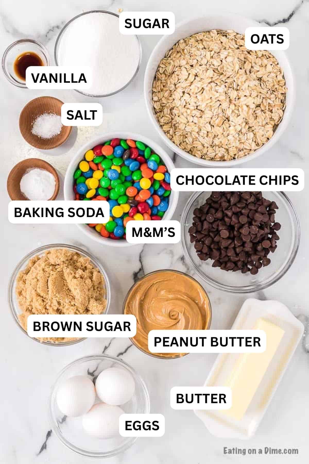 The ingredients required to make the recipe prepared on the countertop which includes oats, chocolate chips, M&M's, peanut butter and more.