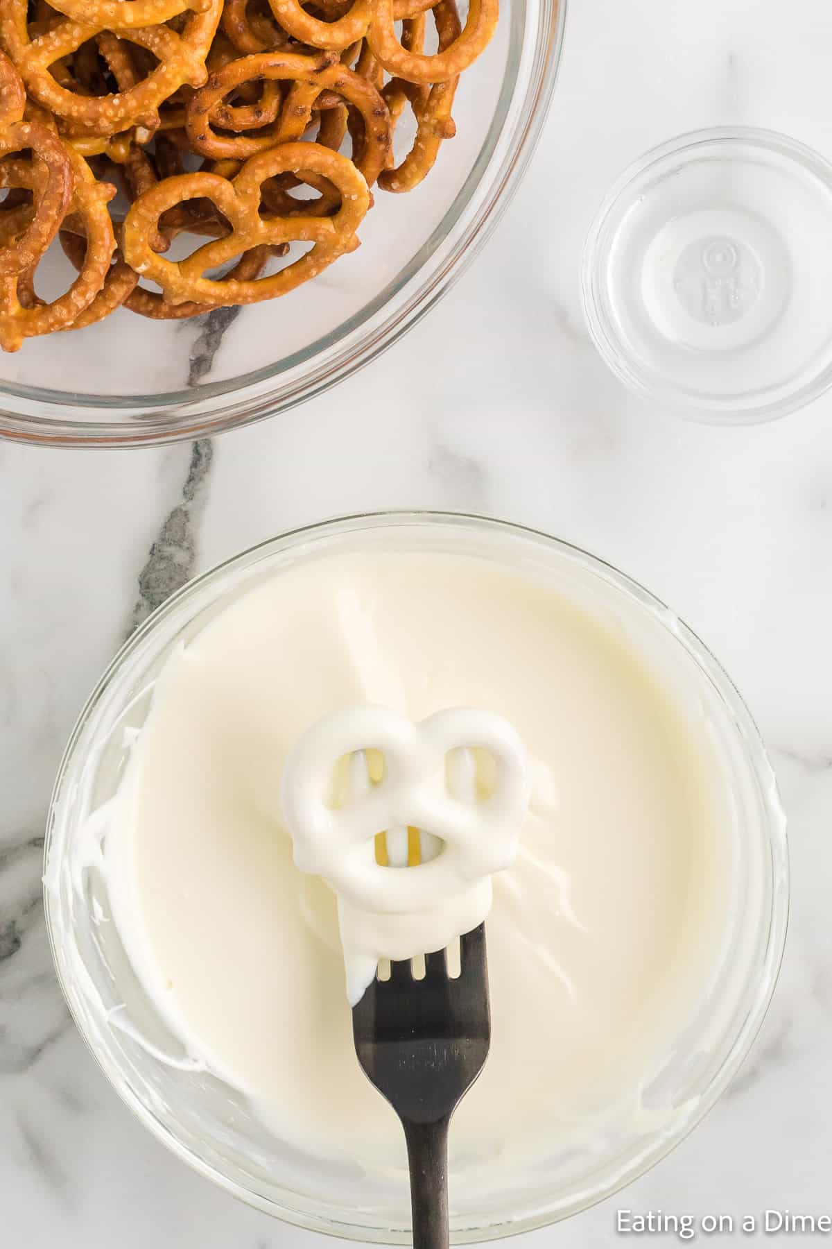 Dipping the white chocolate pretzel in a bowl with a fork