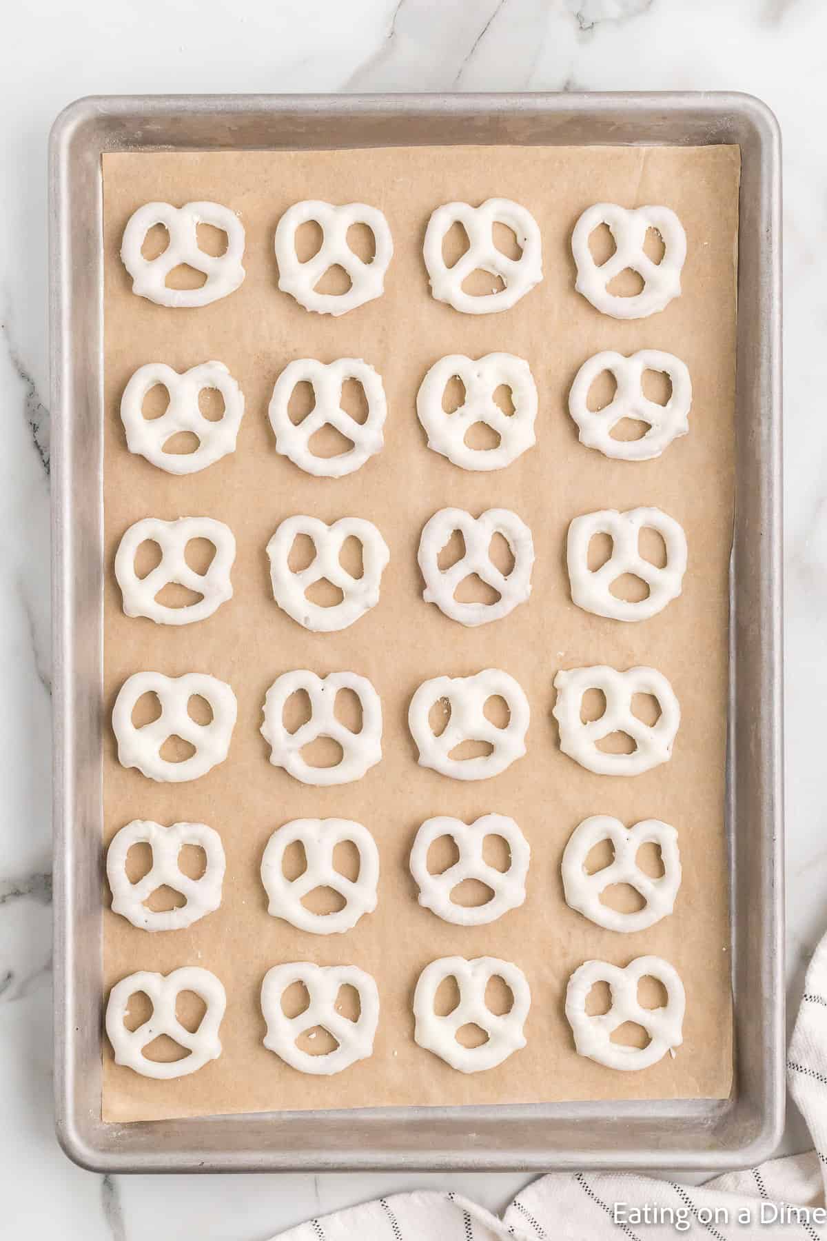 Placing the white chocolate pretzels on a baking sheet