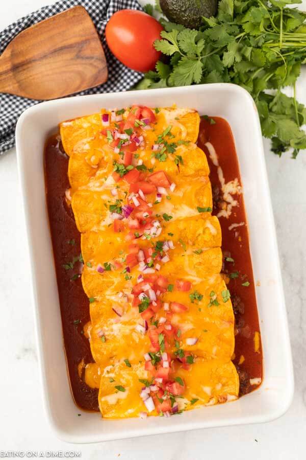 picture of enchiladas in baking dish topped with diced tomatoes and onion