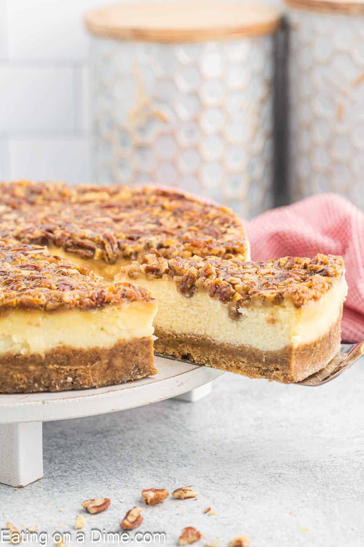 Pecan pie cheesecake on a platter being sliced.