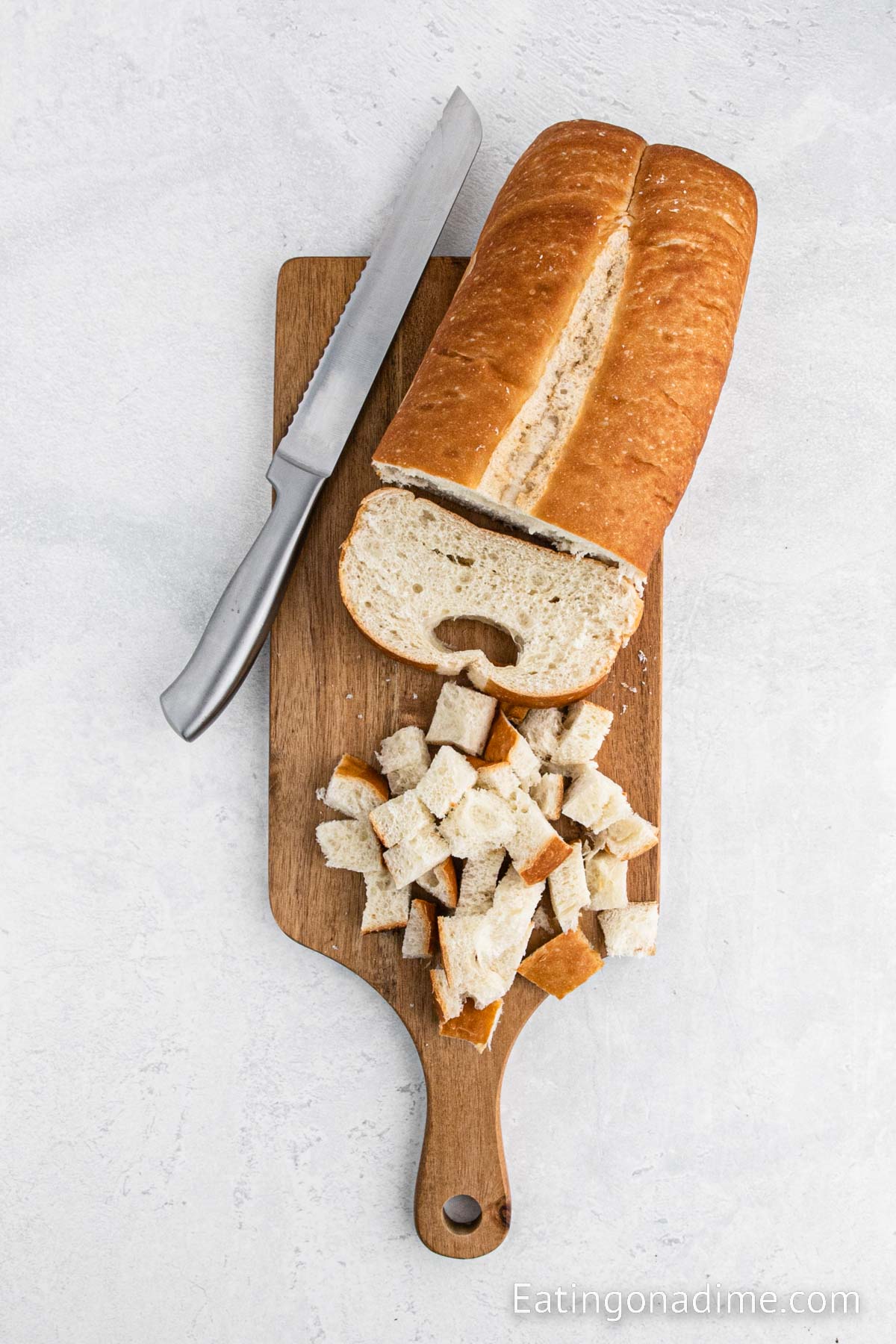 Dicing the bread up into cubes on a cutting board with a knife
