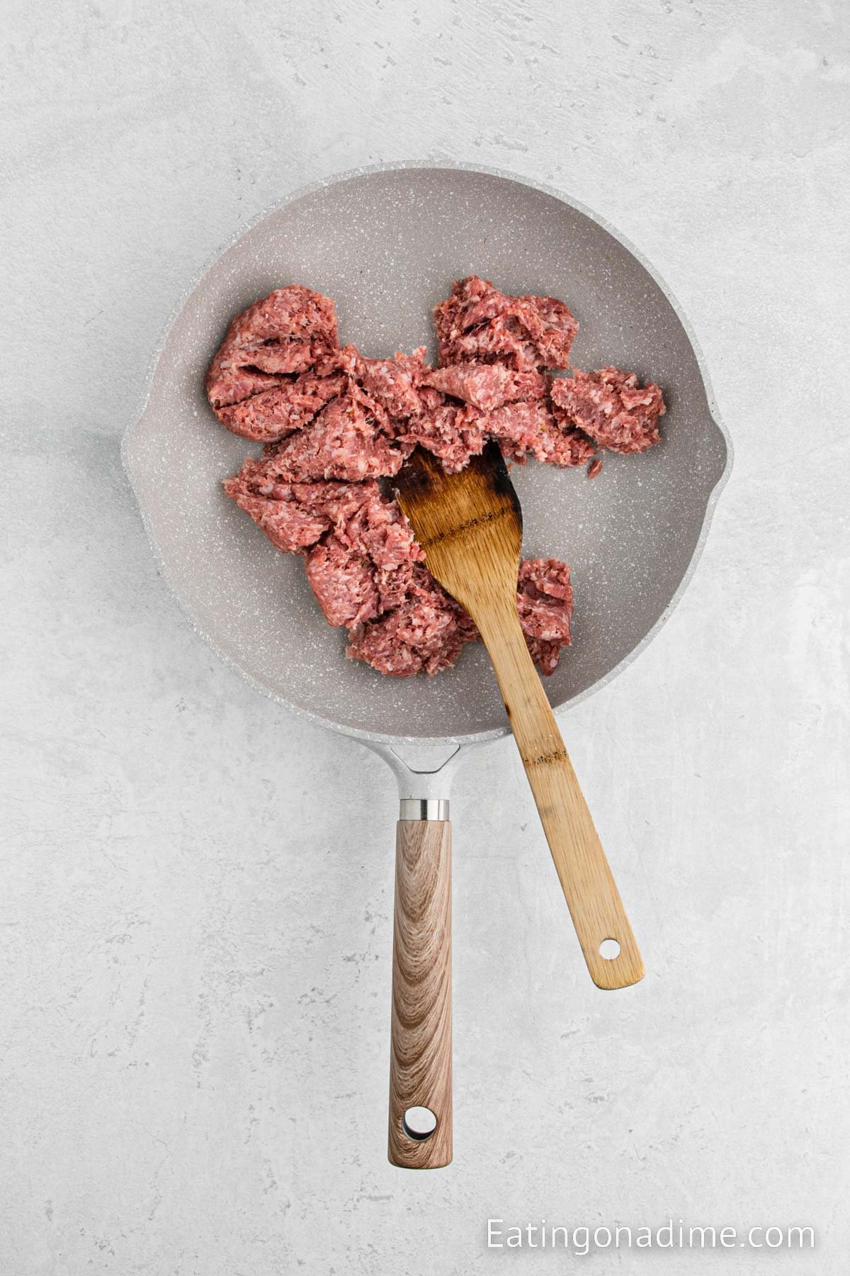 Cooking the sausage in a skillet with a wooden spoon