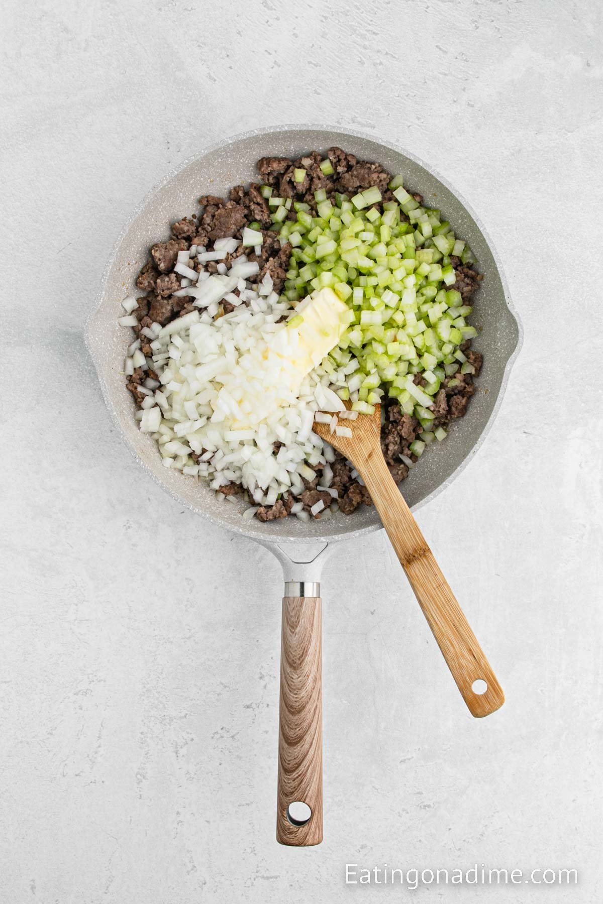 Adding the veggies to the cooked sausage in the skillet