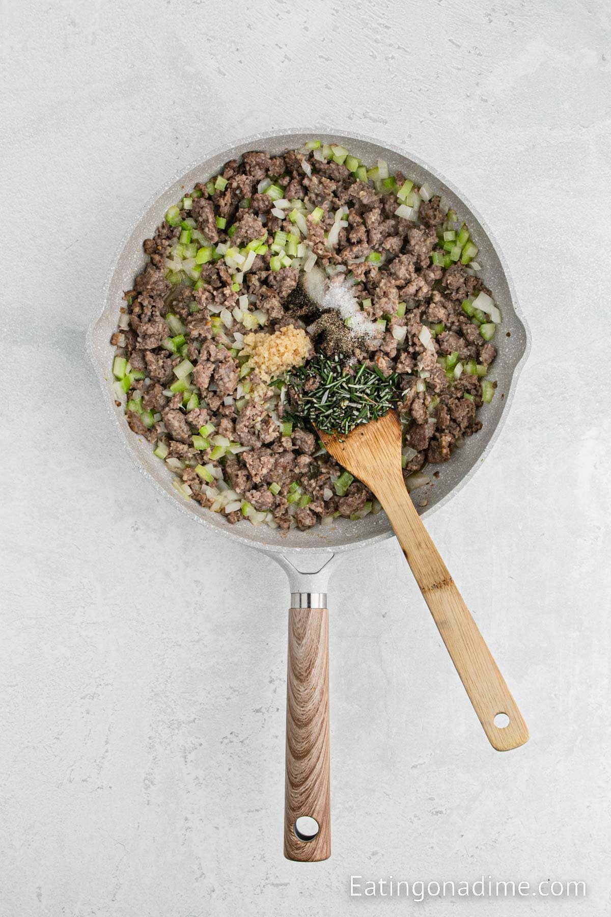 Adding the seasoning to the sausage and veggie mixture in a skillet