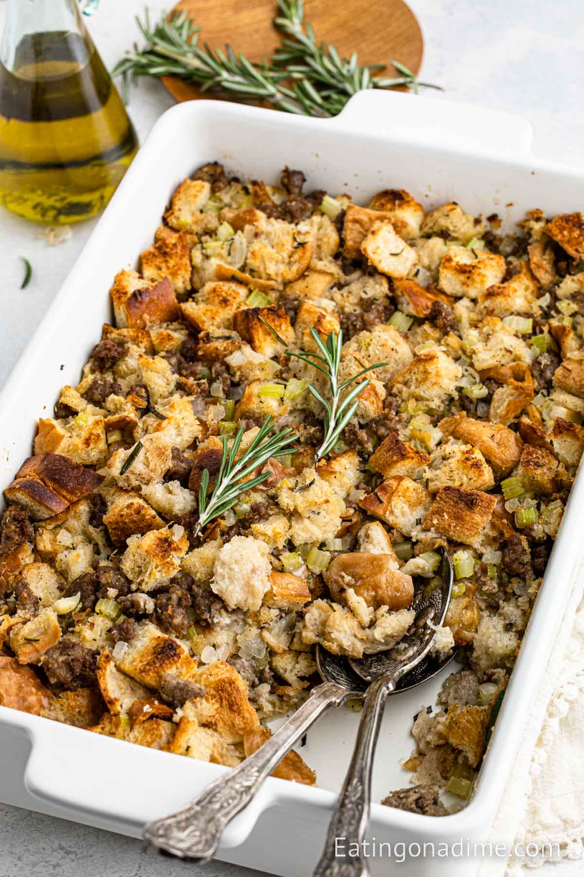 Sausage stuffing in a baking dish with two silver spoons