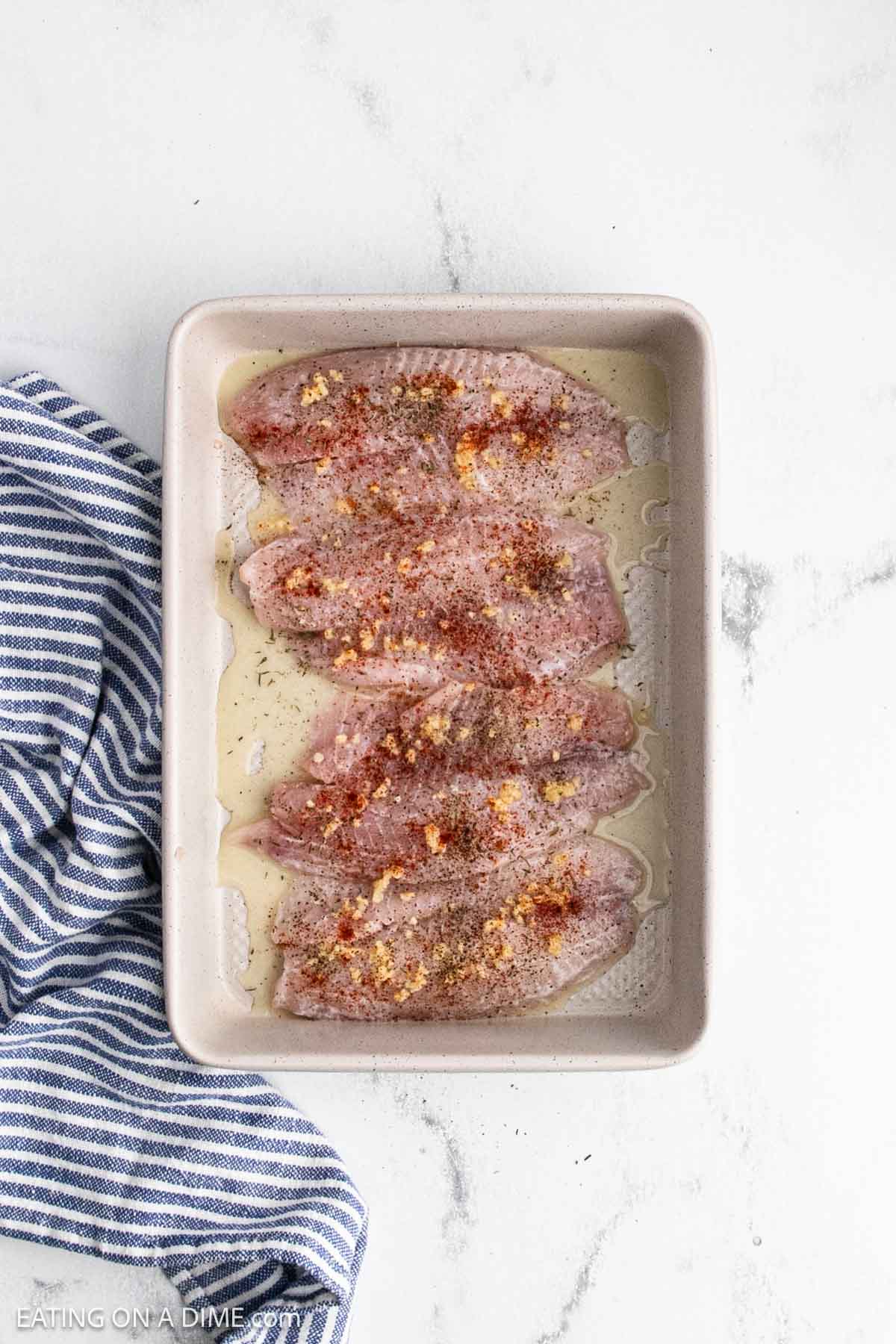 Seasoning and garlic topped the fish in a baking dish.