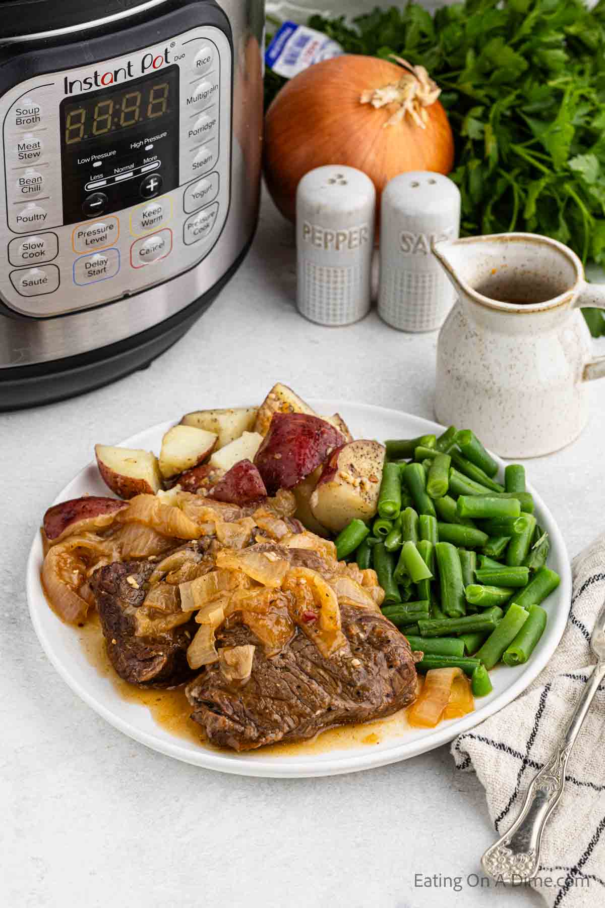 Cooked steak and onions on a plate with green beans and potatoes