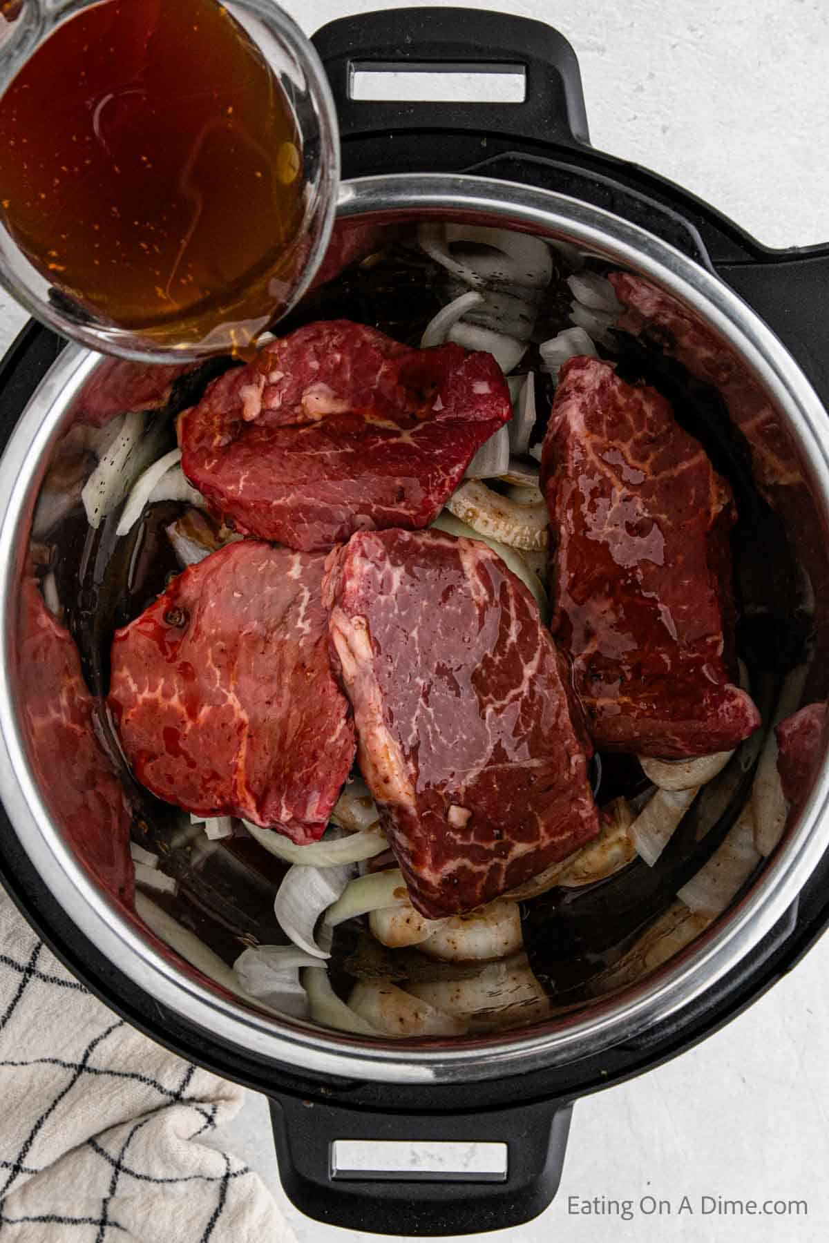 Pouring the broth mixture over the steak in the instant pot