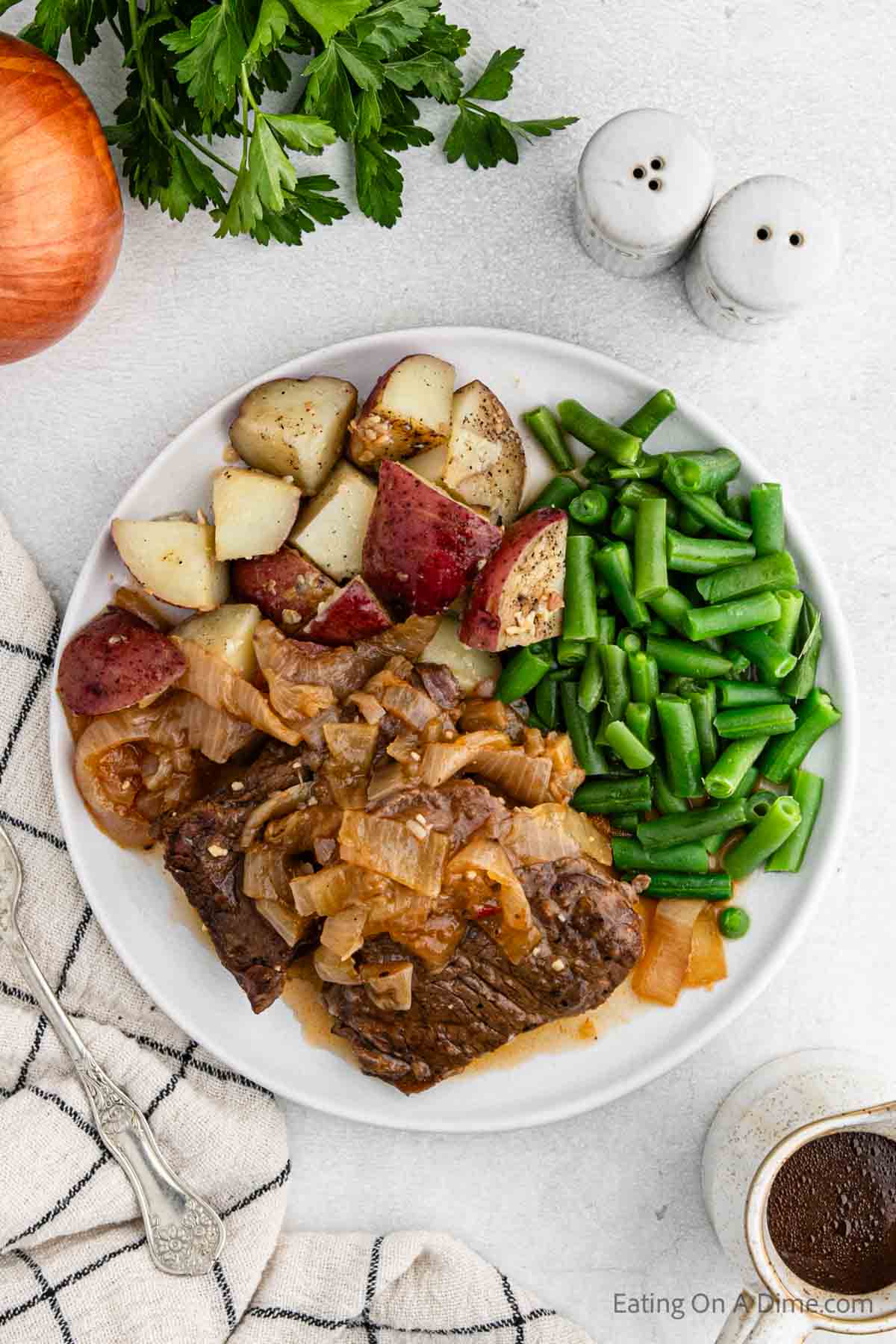 Cooked steak and onions on a plate with green beans and potatoes