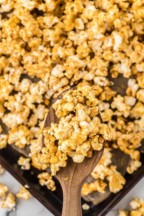 Close up image of a serving of caramel popcorn on a wooden spoon. 