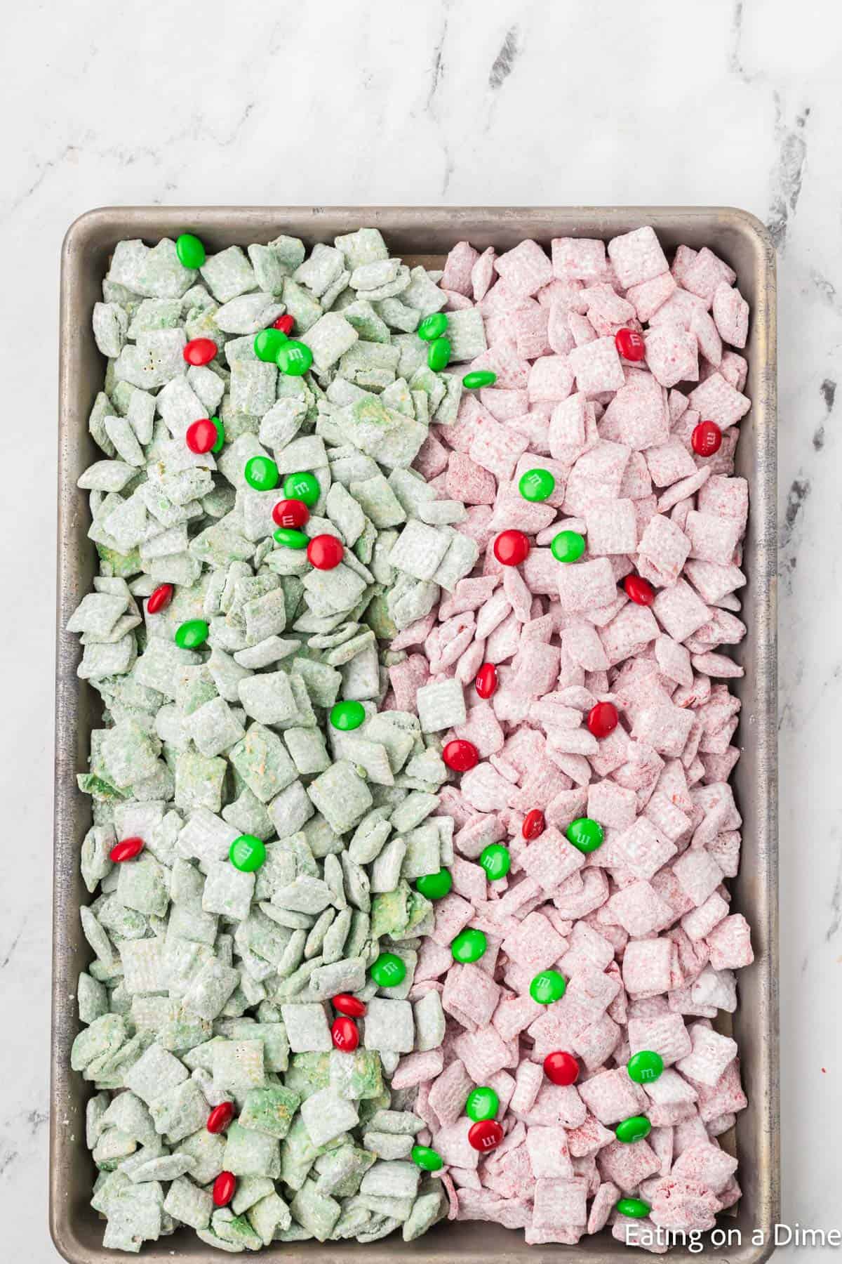 Red and Green Powdered Sugar Coated Chex Cereal on a baking sheet topped with red and green M&Ms