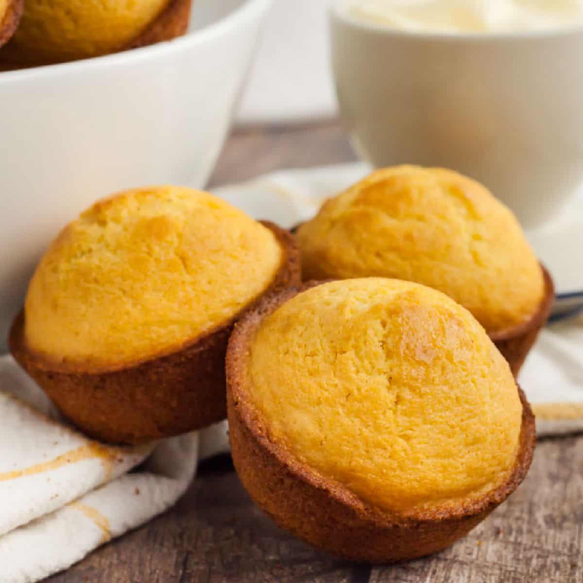 Cornbread Muffins are just so easy to make and much better than those store bought mixes. This cornbread muffin recipe is delicious and a family favorite. 3 Corn Muffins sitting on a kitchen towel.
