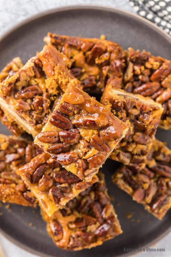 Pecan Pie Cheesecake Bars stacked on a black platter