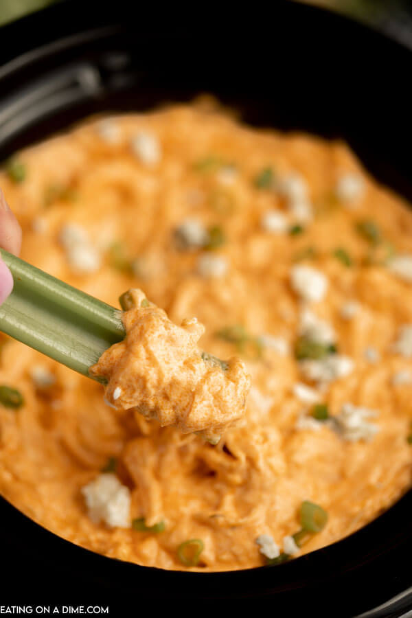 Buffalo Chicken Dip in a slow cooker with a serving on a celery