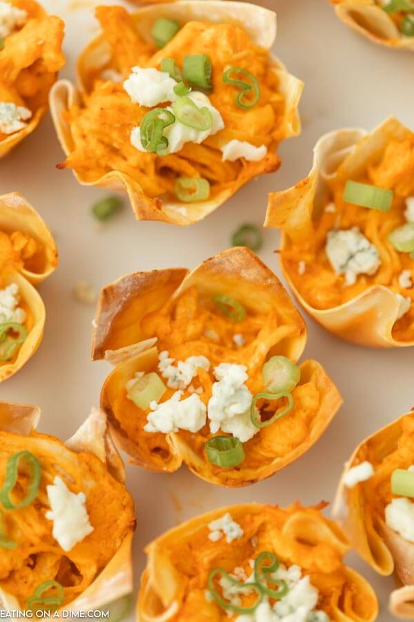 Close up of buffalo chicken wonton cups topped with blue cheese and diced green onions.  