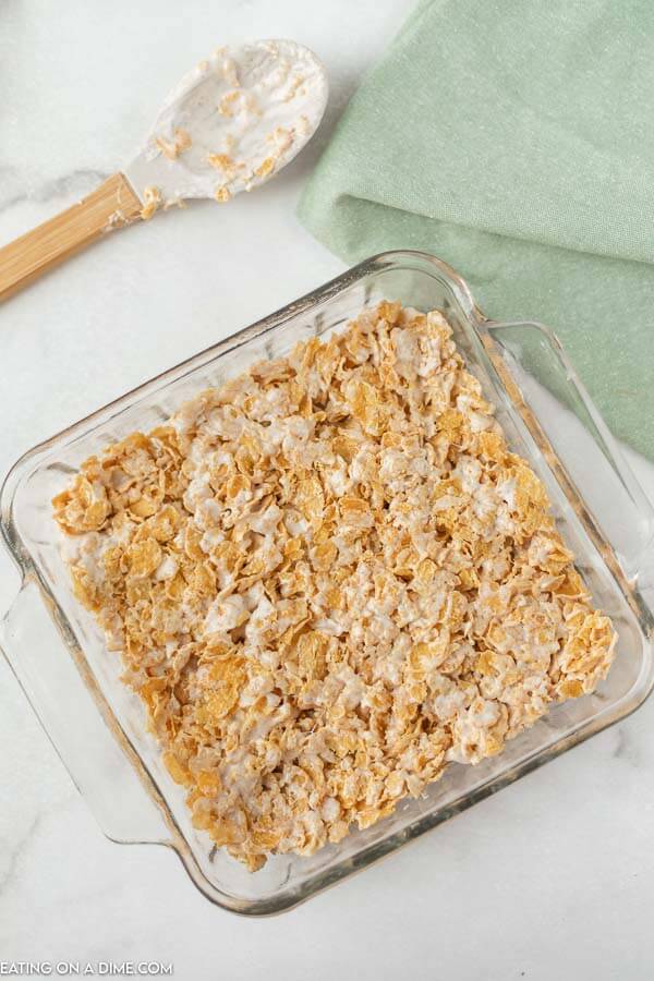 Close up image of cornflake squares in a 8x8 pan with a spatula. 