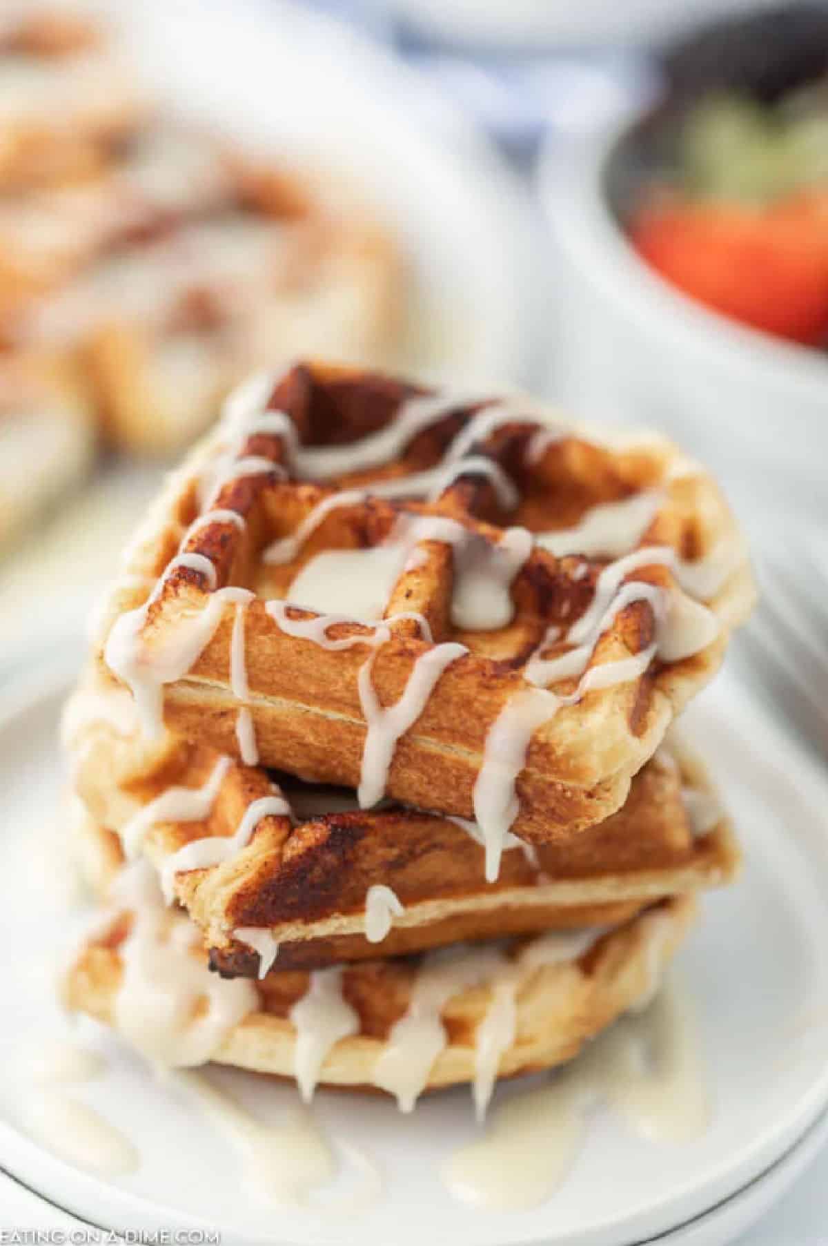 Waffles stacked on top of each other with frosting drizzled on top.