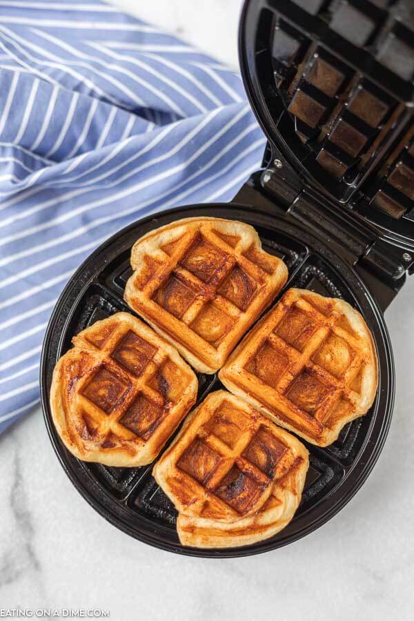 The waffle iron opened showing the cinnamon rolls cooked in the waffle maker.  