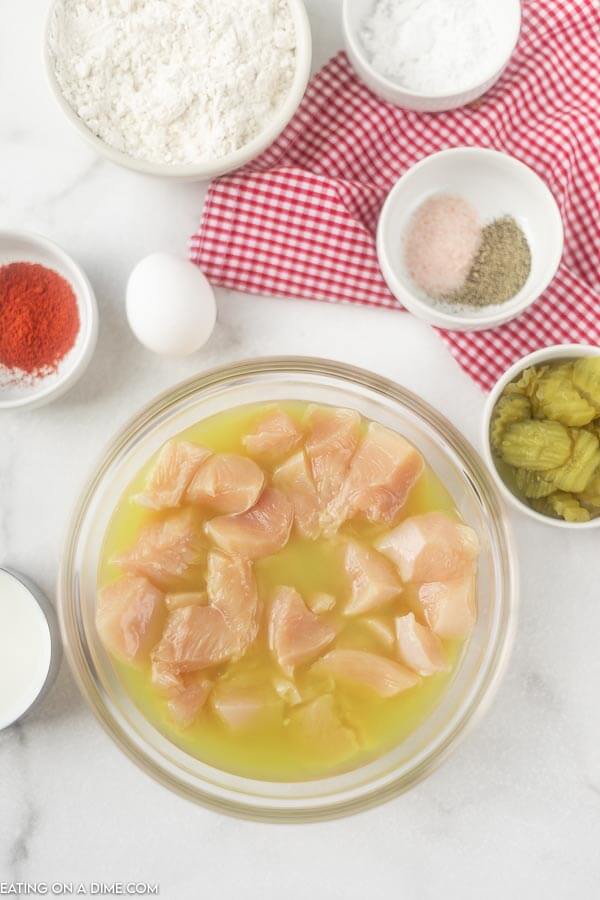 Chicken soaking in bowl of pickle juice. 