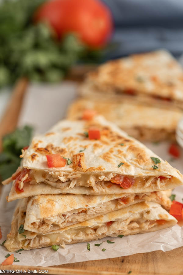 Close up image of chicken quesadilla's stacked with a side of sour cream. 